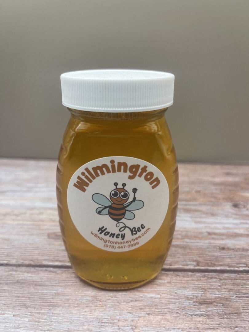 A jar of honey sitting on top of a wooden table.
